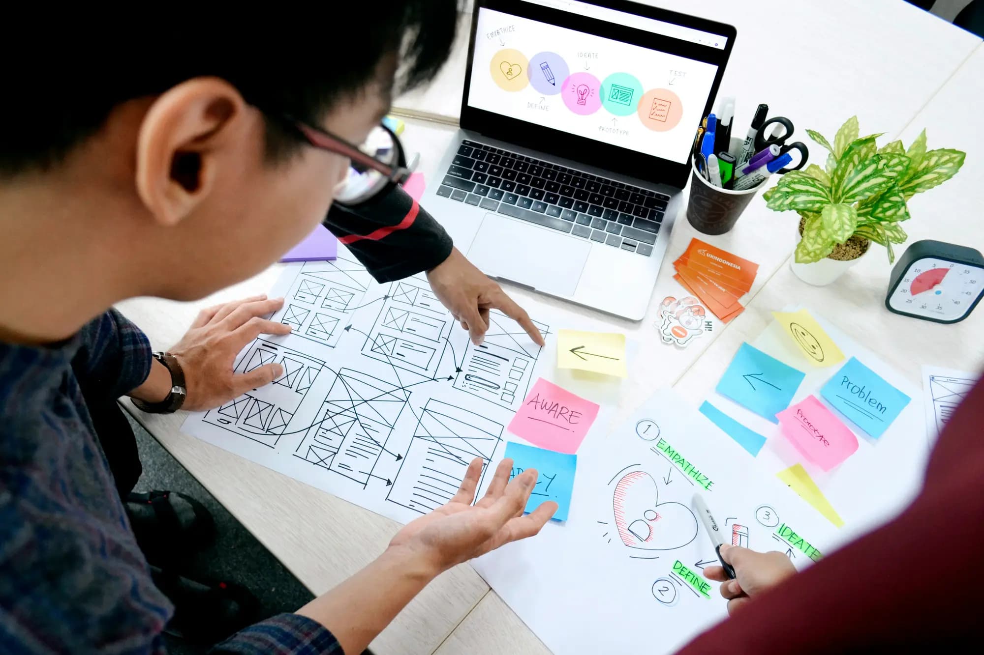 Team sketching website wireframes on paper around a laptop